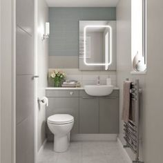 a white toilet sitting next to a sink in a bathroom under a mirror and light