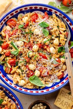 two bowls filled with pasta and vegetables on top of a table next to crackers