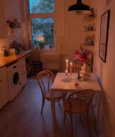 a table with two candles on it in front of a window and a washing machine