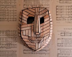 a mask made out of wood sitting on top of sheet music