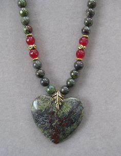 This is a lovely medium sized Heart Shaped Green and Red African Bloodstone Pendant Necklace. It is 16 inches long and adjustable to 21 inches with a lobster clasp and chain. The pendant measures 1 3/4 inches long and wide. The beads in the chain are genuine bloodstone and match the pendant stone with red crystal beads and gold accent beads.    All my jewelry is unique and one of a kind. Similar quality jewelry is priced at double. I source the stone pendants from all over the world. All pendant Spiritual Gemstone Beads Jewelry For Valentine's Day, Heart-shaped Beaded Necklaces With Natural Stones For Gift, Heart-shaped Beaded Necklaces With Natural Stones, Heart-shaped Natural Stone Beaded Necklace For Gift, Heart-shaped Beaded Necklace With Natural Stones For Gift, Spiritual Heart-shaped Beaded Necklaces As Gift, Heart-shaped Natural Stones Necklaces For Jewelry Making, Adjustable Heart-shaped Gemstone Beads Jewelry, Adjustable Heart-shaped Gemstone Bead Necklace