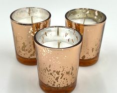 three candles sitting next to each other on top of a white table with brown spots