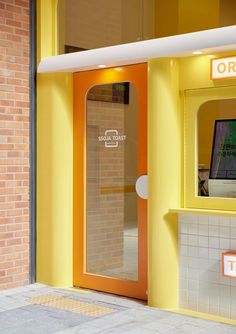 an orange and yellow store front with a computer on the display shelf in the doorway