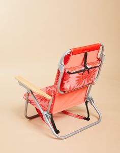 an orange and pink folding chair on a beige background