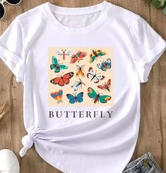 a white t - shirt with butterflies on it and the words butterfly printed in black