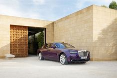 a purple rolls royce parked in front of a building