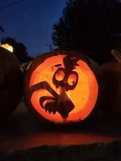 two pumpkins carved to look like cartoon characters with faces on them, one is lit up and the other has an angry face