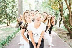 a group of women standing next to each other on a sidewalk in front of trees