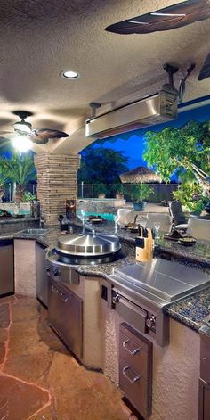 an outdoor kitchen with stainless steel appliances and granite counter tops, built into the ceiling