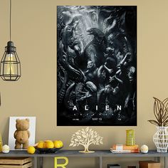 an alien movie poster hangs on the wall above a table with books and other items