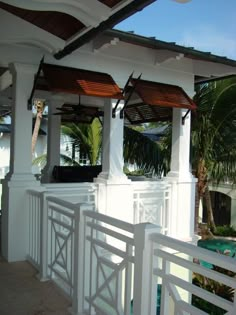 an outdoor covered area with white railings and palm trees