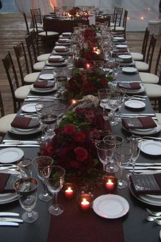 a long table set with place settings and candles