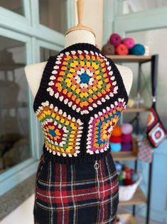 a mannequin wearing a multicolored crochet top and plaid skirt