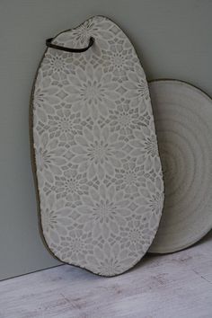 two white plates sitting next to each other on top of a wooden floor in front of a wall