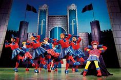 a group of people standing on top of a stage in front of a castle with flags