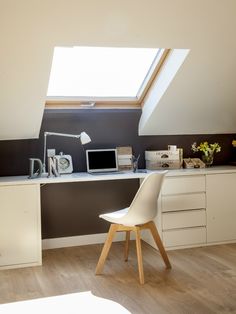 a white chair sitting in front of a desk under a skylight