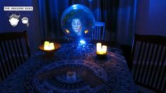 there is a table with candles on it in front of a glass ball that looks like a woman's face