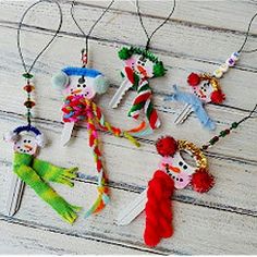 four ornaments are hanging from strings on a white wooden surface, one is decorated with multicolored yarn and the other has a crochet