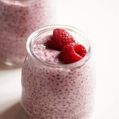 two small jars filled with food and topped with raspberries