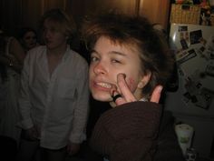 a young woman making the peace sign with her hand while standing in front of a refrigerator