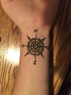 a person with a tattoo on their wrist that has an arrow and compass drawn on it