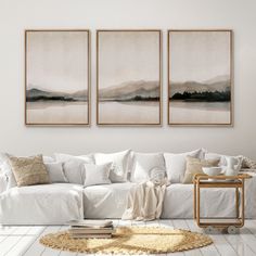 three paintings hang on the wall above a white couch in front of a coffee table