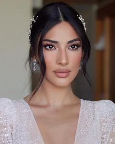 a woman in a white dress with pearls on her head and long black hair wearing a tiara