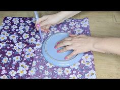 a woman with pink nails is holding a blue plate on a purple flowered cloth