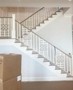 a cardboard box sitting in front of a stair case next to a white railing and banister