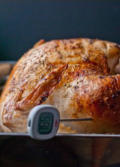 a cooked chicken on a pan with an electronic thermometer in front of it