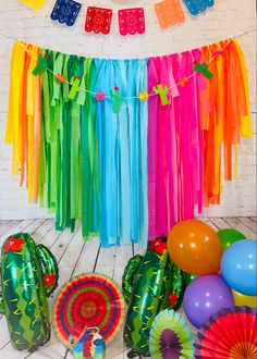 colorful party decorations and streamers in front of a white brick wall