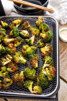 broccoli florets on a grill with chopsticks next to it