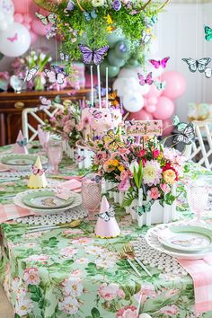 the table is set with pink, green and white decorations for a butterfly themed birthday party