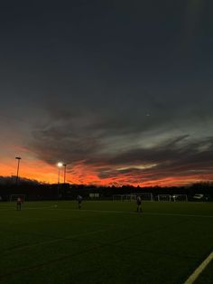 the sun is setting over a soccer field with players on it and one ball in the air