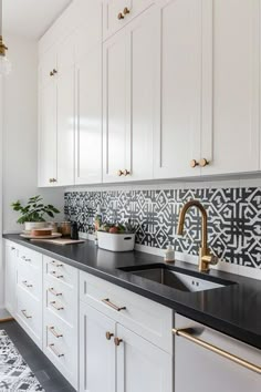 a kitchen with white cabinets and black counter tops, gold faucets and brass pulls