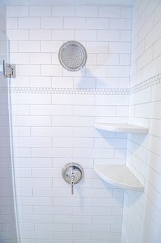 a shower with white tile walls and shelves