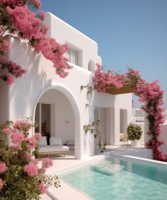 an outdoor swimming pool with pink flowers on the walls and in between two white buildings