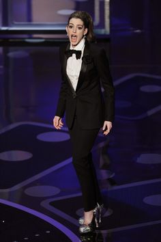 a woman in a tuxedo walks down the runway with her mouth open and tongue out