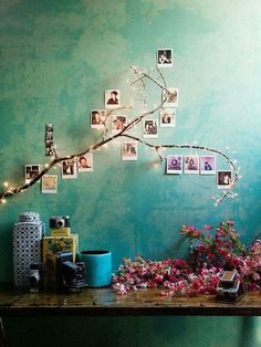 a table with flowers and pictures on it in front of a green wall, along with other items