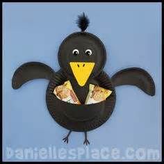 a paper plate shaped like a black bird with a piece of food in it's beak