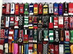 many different colored scarfs are hanging on the wall in front of a display case