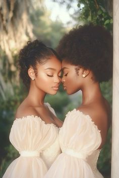 two women in white dresses standing next to each other with their faces close together and trees behind them