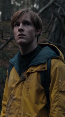 a man standing in the woods wearing a yellow jacket