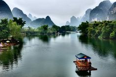 a boat floating on top of a river surrounded by mountains