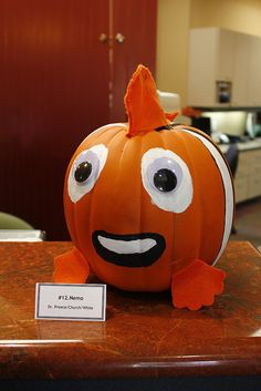 a pumpkin with googly eyes sitting on top of a table