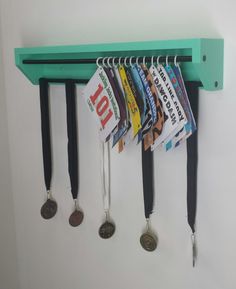 a green shelf with several medals hanging from it's hooks and two coin holders