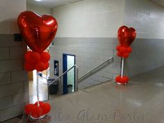 two red heart shaped balloons are on the ground in front of a stairwell with stairs