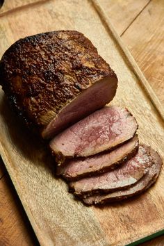 sliced meat sitting on top of a wooden cutting board