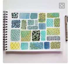 an open notebook with various designs on it and a pen next to the book cover