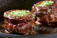 two steaks are being cooked in a skillet